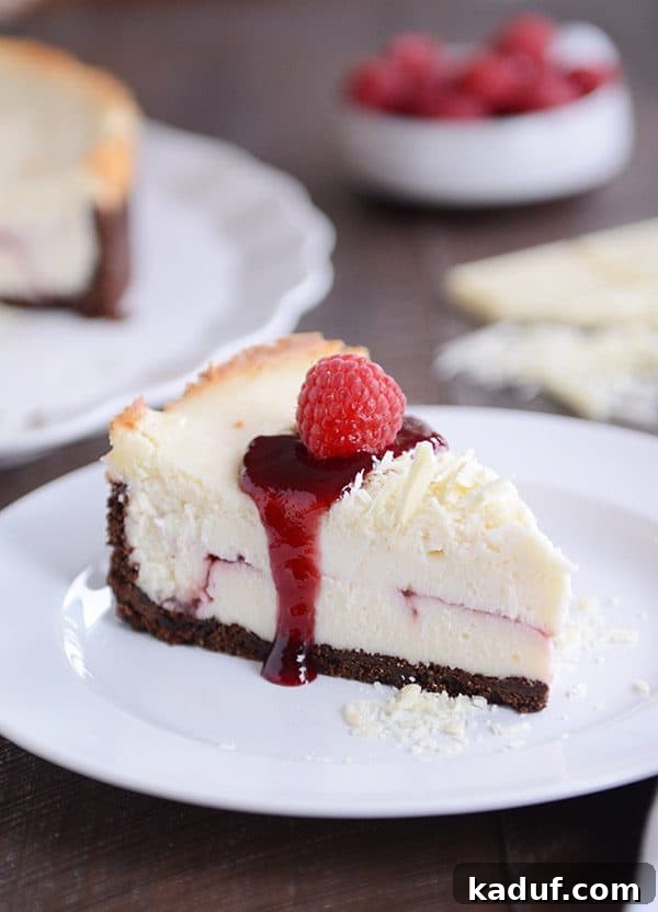 Exquisite White Chocolate Raspberry Truffle Cheesecake 2 A perfectly sliced piece of white chocolate raspberry cheesecake on a pristine white plate, showcasing layers of creamy white chocolate, vibrant raspberry swirls, and a rich chocolate cookie crust. Garnished with fresh raspberries and delicate white chocolate shavings.
