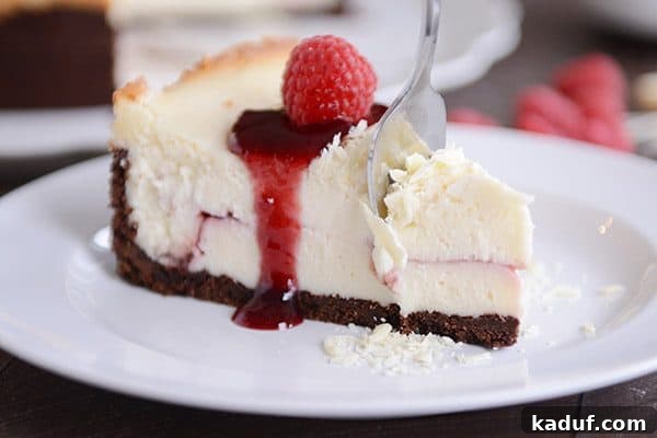 Exquisite White Chocolate Raspberry Truffle Cheesecake 4 A fork taking a delicious bite out of a slice of White Chocolate Raspberry Truffle Cheesecake, highlighting the smooth texture and the raspberry swirl within the creamy layers.
