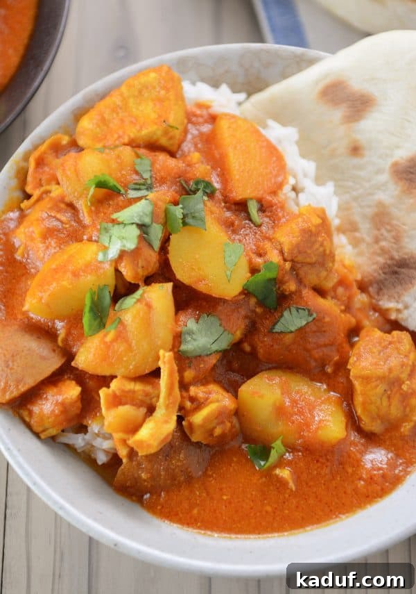 Creamy Instant Pot Indian Butter Chicken with Tender Potatoes 4 A close-up of Instant Pot Indian butter chicken and potato curry, perfectly portioned over white rice in a bowl.