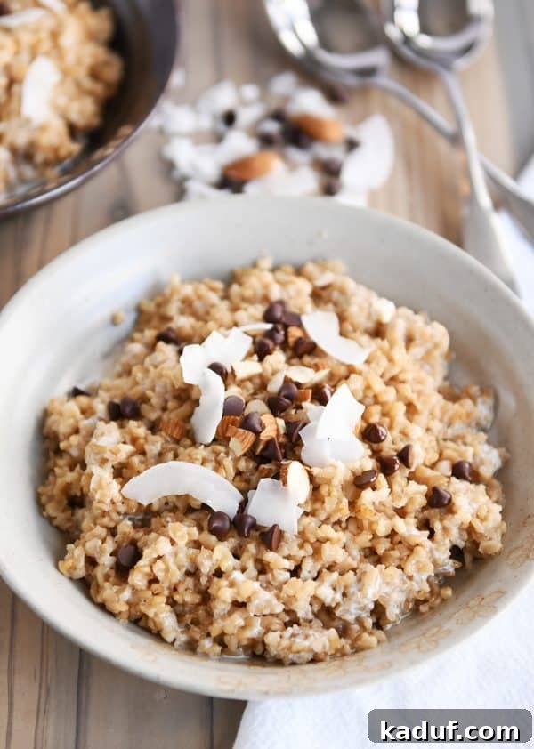 Creamy Coconut Milk Steel Cut Oatmeal in a white bowl, adorned with chocolate chips, sliced almonds, and coconut flakes. A delicious and wholesome breakfast option.