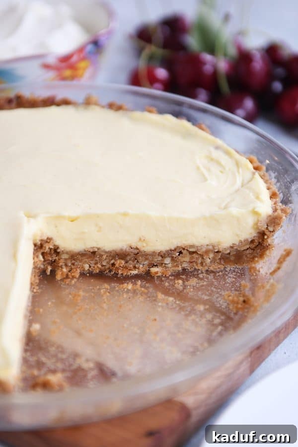 Creamy Berry Delight Pie with Toasted Pecan Graham Crust 3 Berries and cream pie in pie plate with a piece taken out.