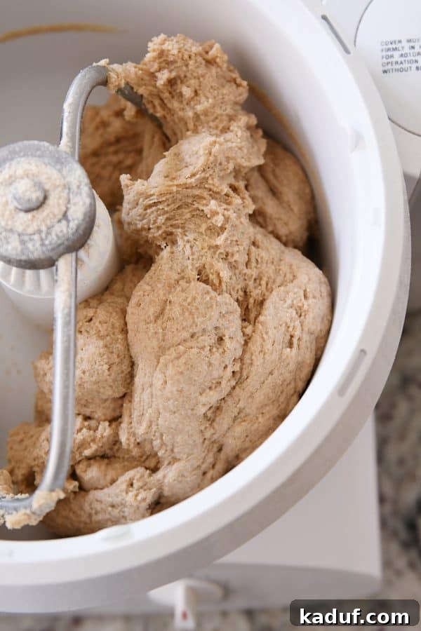 Effortless KitchenAid Small Batch Soft Fluffy Whole Wheat Bread 3 Whole wheat bread dough mixing in a Bosch stand mixer, showcasing the process.