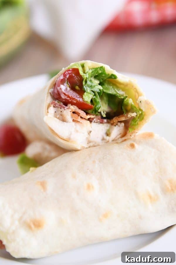 Weeknight Chicken BLT Wraps with Creamy Southwest Zing 4 A half-eaten chicken BLT burrito on a white plate, showing the layers of ingredients.
