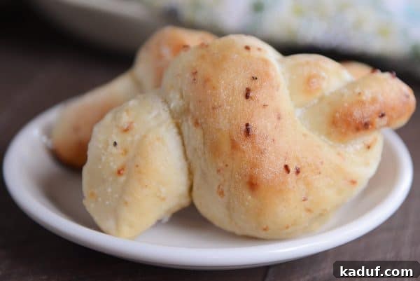 Quick Cheesy Parmesan Knots 14 Two soft, golden Parmesan breadstick knots presented neatly on a white plate, invitingly ready to be enjoyed as a snack or side dish.