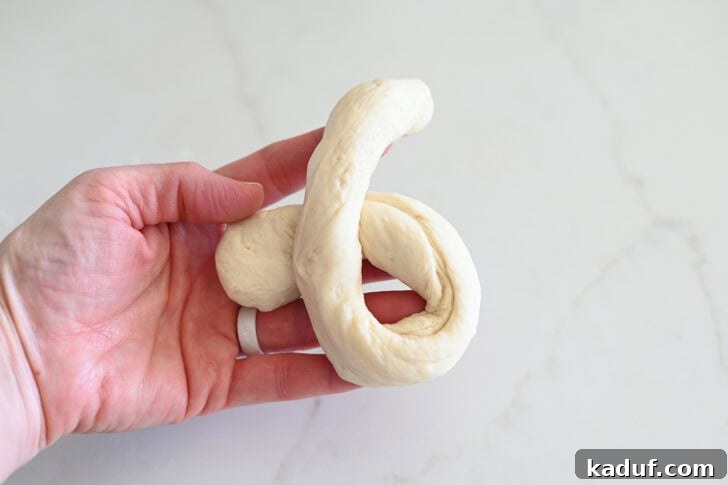 Quick Cheesy Parmesan Knots 8 Hands demonstrating the first step of knot formation, twisting one end of the breadstick strip over the other to create an initial loop for the knot.