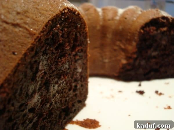 Velvet Fudge Bundt Cake 3 A stunning chocolate bundt cake on a white platter, with one slice carefully removed, inviting you to taste its richness.