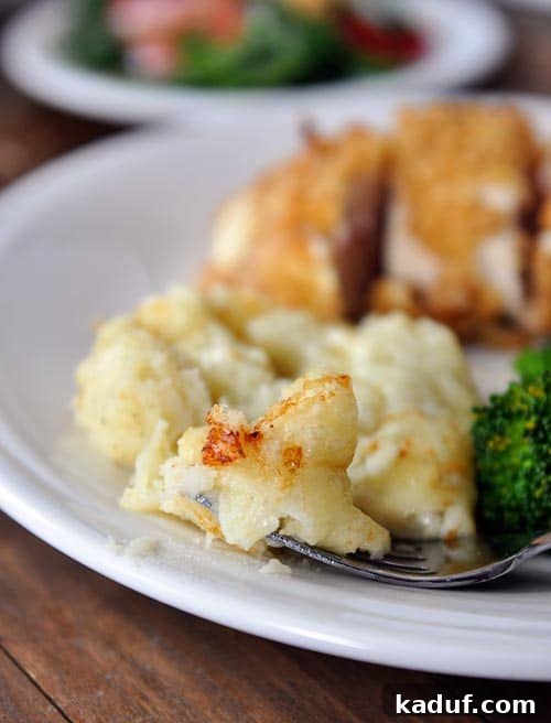 Silky Chantilly Potatoes 2 Creamy chantilly potatoes and a chicken breast on a white plate, showcasing the golden, cheesy texture.