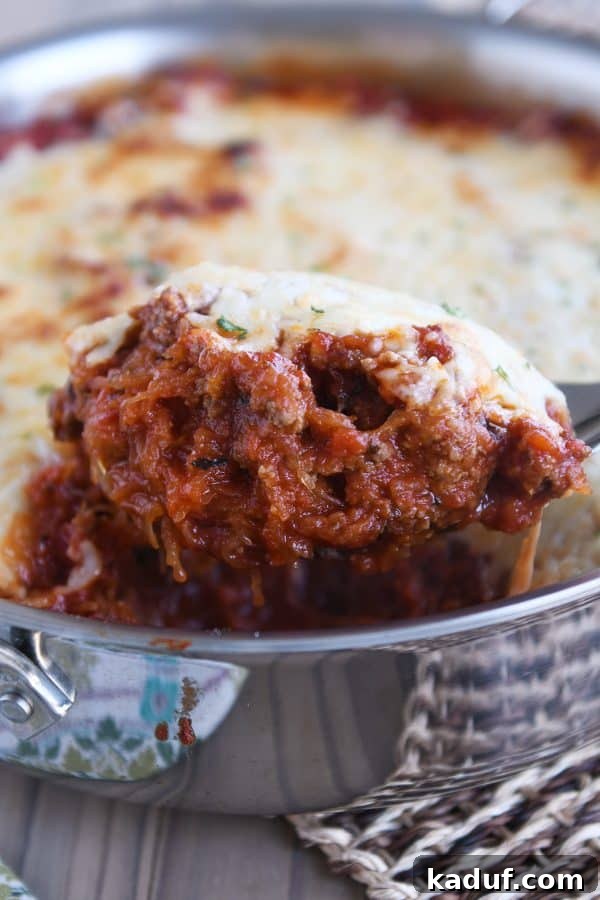 Effortless Weeknight Spaghetti Squash Casserole 2 Scoop of Spaghetti squash spaghetti bake topped with cheese in pan, showcasing golden melted cheese and vibrant sauce.