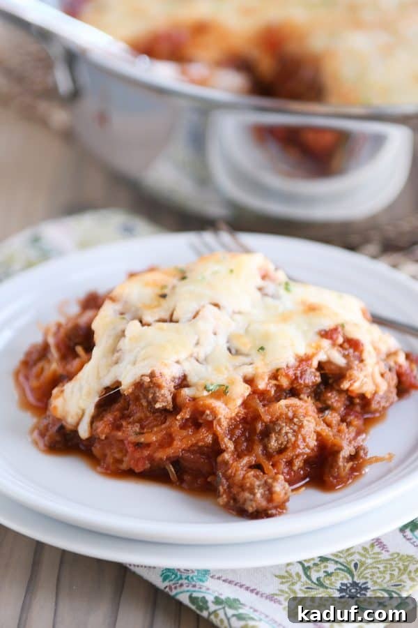 Effortless Weeknight Spaghetti Squash Casserole 3 A serving of spaghetti squash bake with melted cheese on a white plate, highlighting the texture of the squash strands.