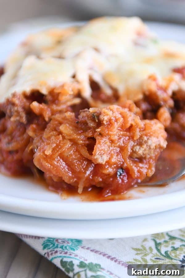 Effortless Weeknight Spaghetti Squash Casserole 4 A forkful of spaghetti squash spaghetti bake, showing strands of squash coated in sauce and cheese, ready to eat.