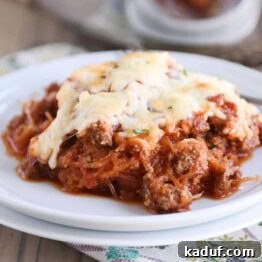 Effortless Weeknight Spaghetti Squash Casserole 7 A top-down view of a serving of Easy Spaghetti Squash Spaghetti Bake on a white plate, garnished with fresh herbs.