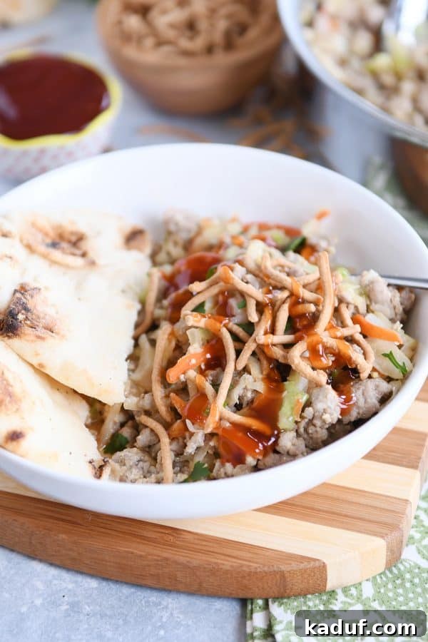 Deconstructed Egg Roll Skillet 2 Ground turkey, cabbage, and naan bread in a white bowl, drizzled with sweet and sour sauce.