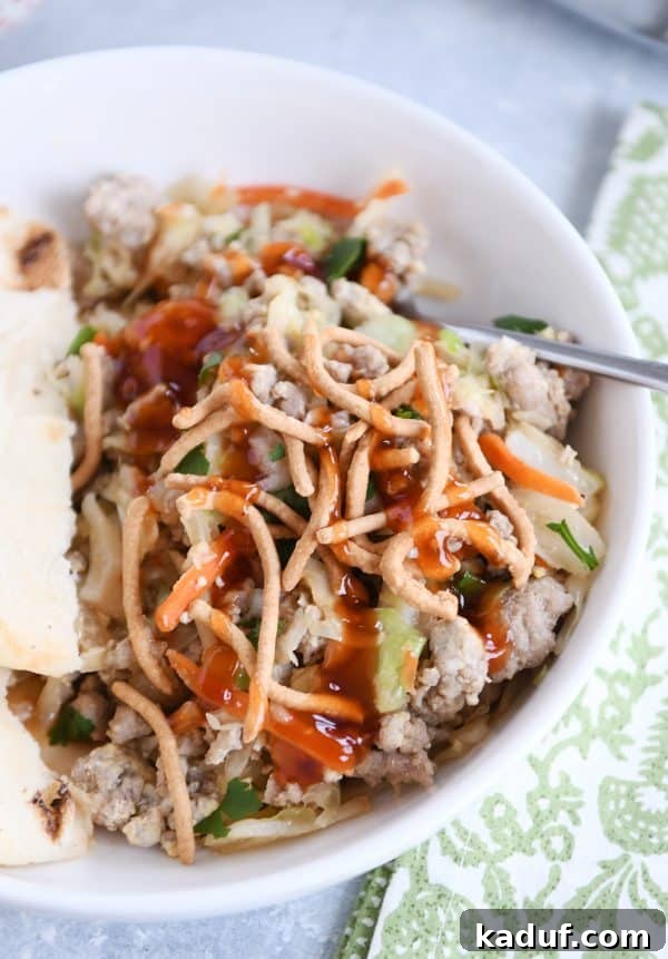 Deconstructed Egg Roll Skillet 5 Egg roll skillet meal with ground turkey, cabbage, and naan, drizzled with sweet and sour sauce in a white bowl.