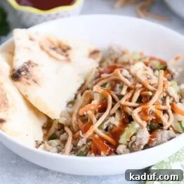 Deconstructed Egg Roll Skillet 6 Ground turkey, cabbage, naan in white bowl drizzled with sweet and sour sauce.