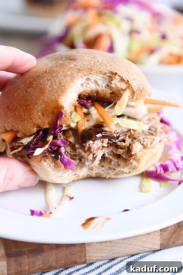 Effortless Honey Balsamic Pulled Pork Sandwiches Instant Pot and Slow Cooker Magic 2 A delicious honey balsamic BBQ pork sandwich with a bite taken out, served on a white plate, showcasing the succulent pulled pork and vibrant sauce.