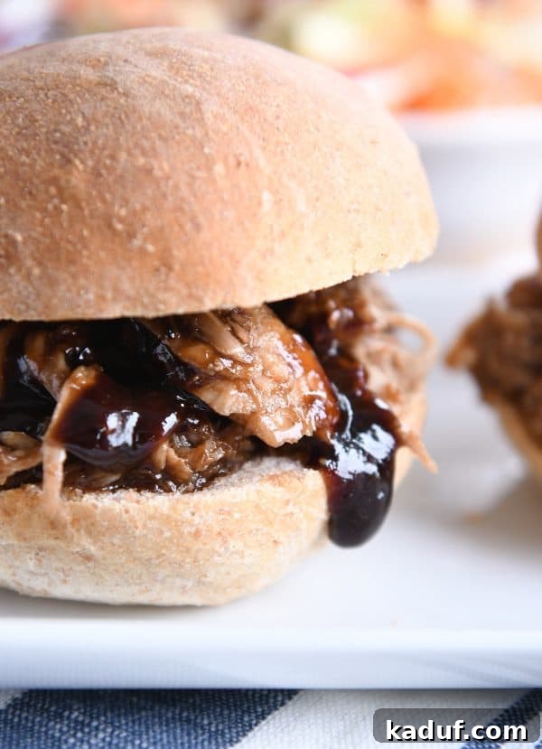 Effortless Honey Balsamic Pulled Pork Sandwiches Instant Pot and Slow Cooker Magic 3 A close-up view of a perfectly crafted honey balsamic BBQ pork sandwich on a rustic white tray, highlighting the rich texture of the pulled pork and glistening sauce.