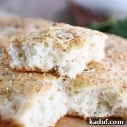 Easy focaccia bread with piece on top of loaf.
