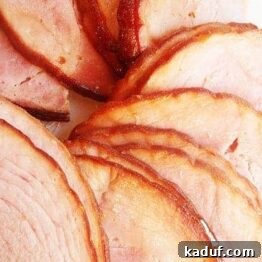 Golden Maple Glazed Ham 3 A perfectly glazed spiral-cut ham, ready to be carved, showcasing its golden-brown, caramelized crust.
