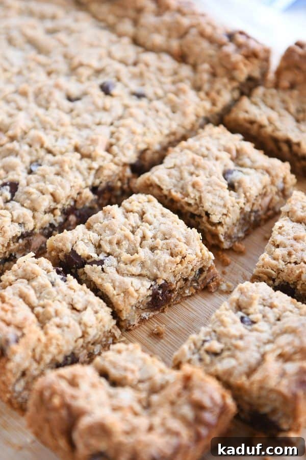 Slab of monster cookie bars cut into squares on a rustic wooden board, ready to be enjoyed.