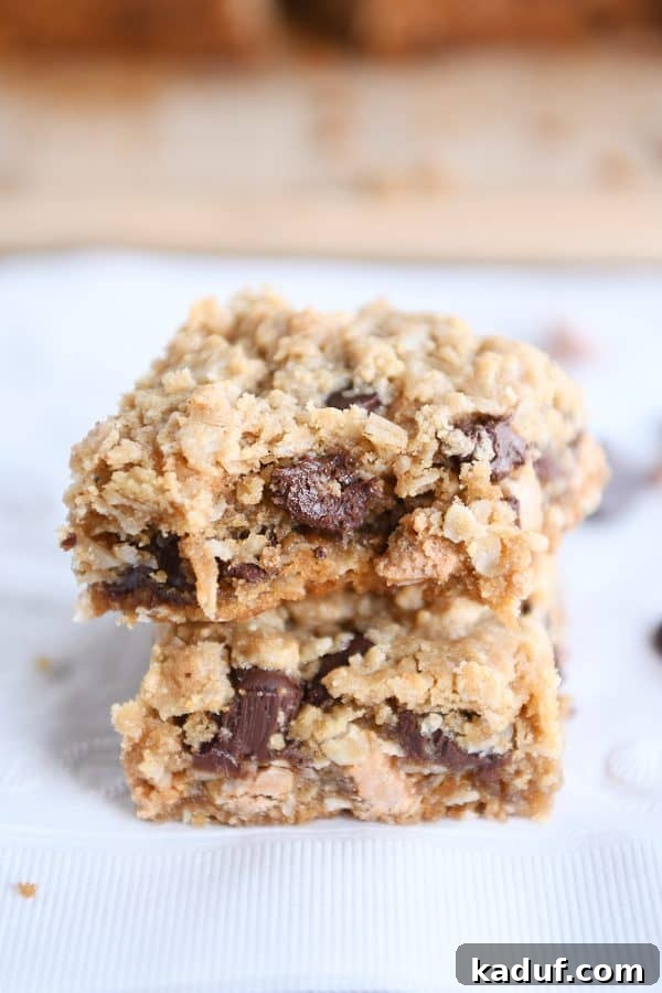 Two soft and chewy butterscotch PB monster cookie bars stacked on each other with a tempting bite taken out.