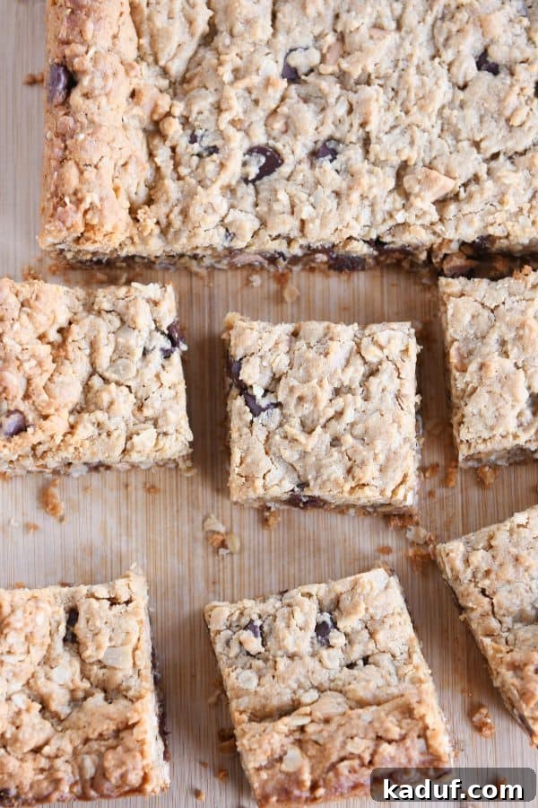 Top down shot of perfectly cut monster cookie bars on a light wooden board, showcasing their inviting texture.