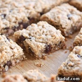 Slab of monster cookie bars cut into squares on wood board.