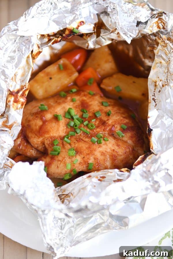 Tropical BBQ Chicken Foil Dinners 2 An opened BBQ Hawaiian chicken foil packet revealing succulent chicken, colorful bell peppers, and juicy pineapple chunks inside, ready to be enjoyed.