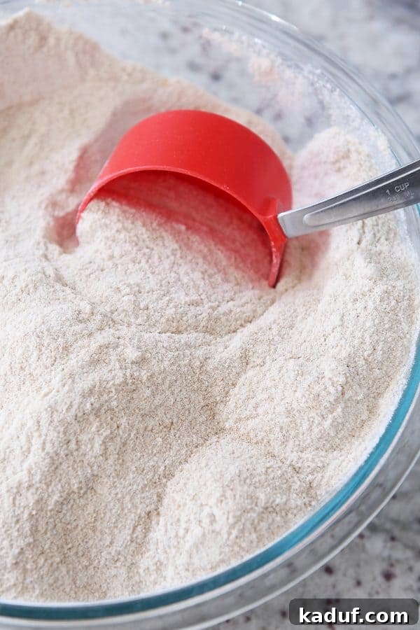 Mastering Yeast Baking: Modern Techniques 8 Scooping whole wheat flour out of bowl.