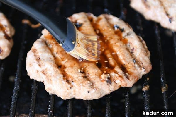 Tropical Teriyaki Turkey Burgers with Grilled Pineapple 5 Brushing a perfectly grilled turkey burger with savory teriyaki sauce, enhancing its flavor and shine.