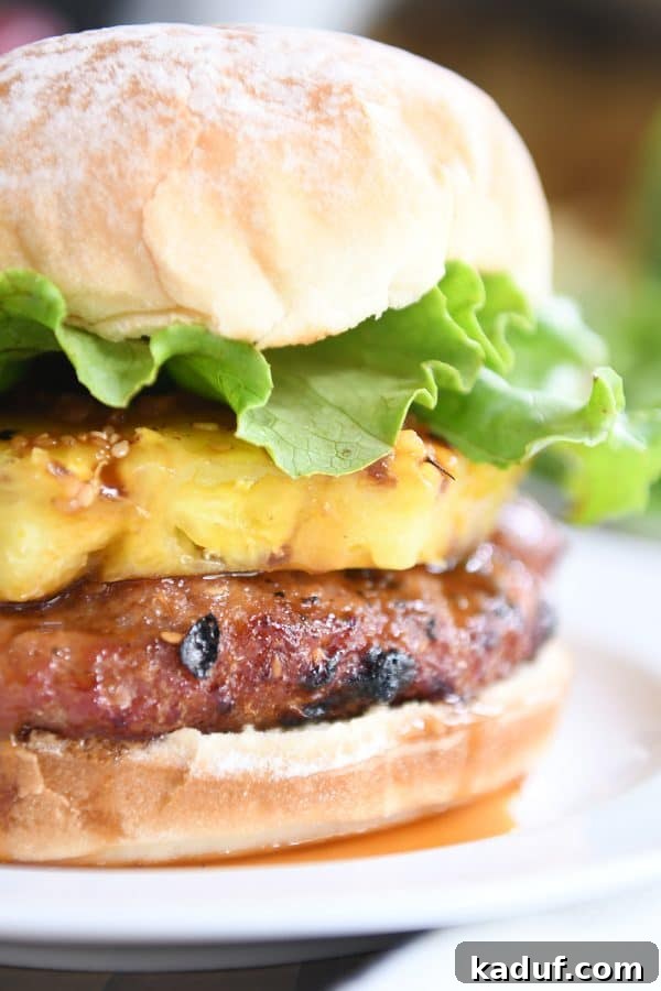 Tropical Teriyaki Turkey Burgers with Grilled Pineapple 6 Close-up of a mouth-watering Teriyaki Turkey Burger with grilled pineapple, lettuce, and a soft bun, ready to be enjoyed.