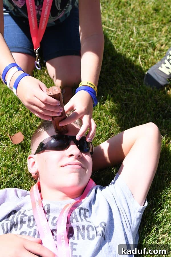 Friday Focus: Mastering the Summer Months 10 A child participating in a playful family Olympic game, balancing a snack on their forehead, eliciting smiles.
