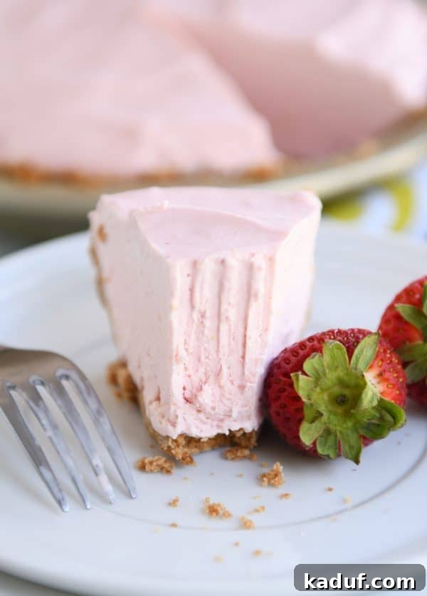 Pink Lemonade Strawberry Bliss Pie 2 Half-eaten slice of creamy frozen strawberry lemonade pie on a white plate, showcasing its vibrant layers.
