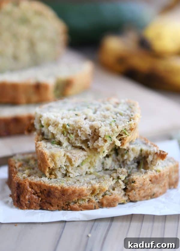 Moist Zucchini Banana Bliss 3 Two slices of zucchini banana bread, with the top slice gently broken to show the soft, fluffy interior.