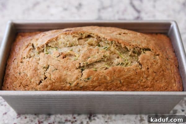Moist Zucchini Banana Bliss 7 A perfectly baked loaf of zucchini banana bread, golden brown and still in its metal pan, fresh from the oven.
