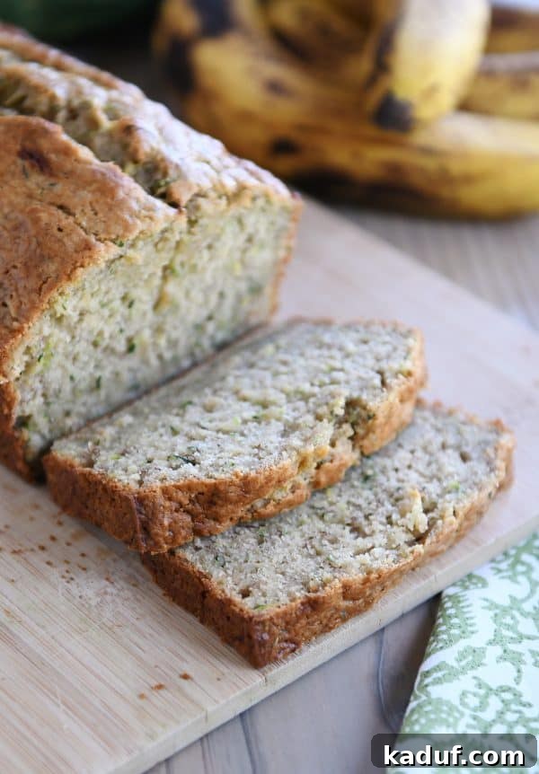 Moist Zucchini Banana Bliss 8 A beautifully sliced loaf of zucchini banana bread displayed on a rustic wood cutting board, ready to be served.