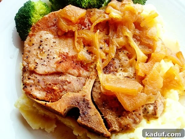 Bone-in pork chop with cooked onions on top.