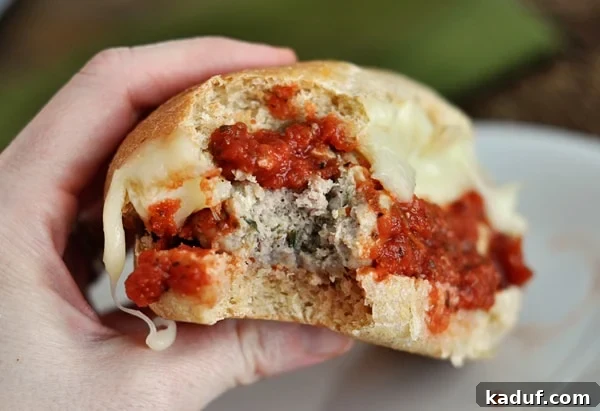 Hearty Italian Meatball Subs 3 A close-up shot of an Italian meatball sub with a bite taken out, showing the juicy meatballs and melted cheese.