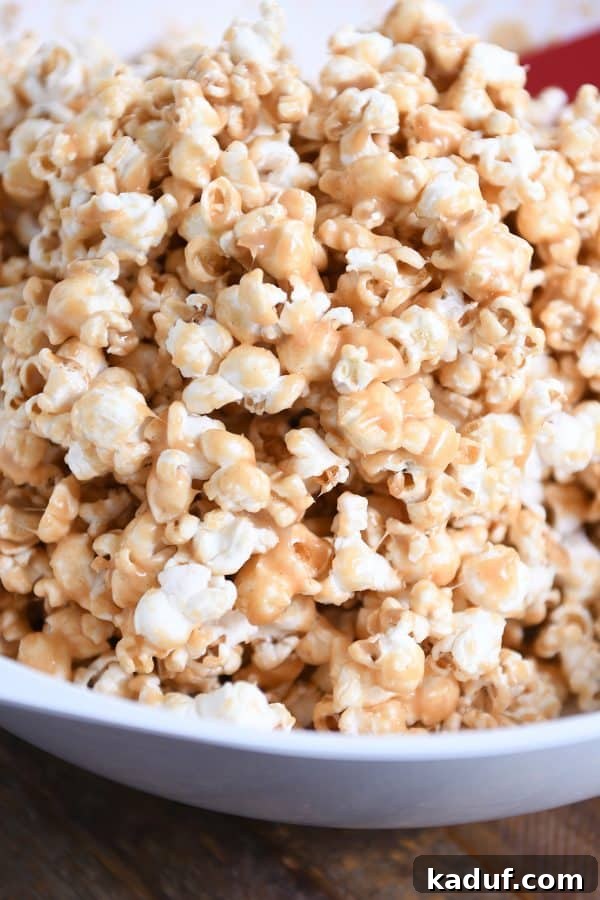 Gooey Peanut Butter Popcorn Bliss 2 A white bowl generously filled with soft and chewy peanut butter caramel popcorn, ready to be enjoyed as a delicious sweet and salty snack.