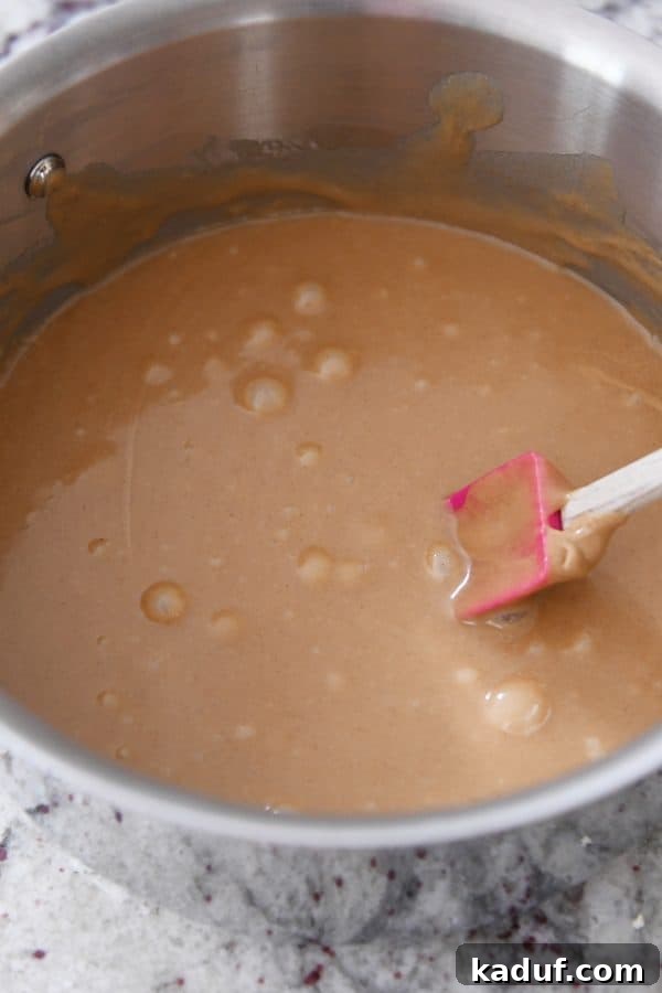 Gooey Peanut Butter Popcorn Bliss 8 The peanut butter caramel mixture in a saucepan, stirred until smooth and creamy, ready to be poured over popcorn.