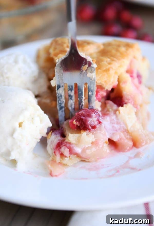 Thanksgivings Beloved Apple Cranberry Pie 4 Slice of apple cranberry pie on white plate with ice cream.