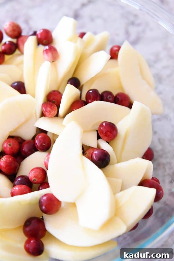 Thanksgivings Beloved Apple Cranberry Pie 5 Glass bowl with sliced apples and fresh cranberries.