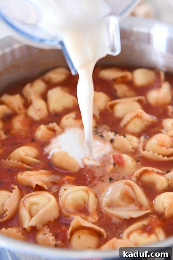 A hand pouring a mixture of milk and flour into a pot of simmering creamy Tuscan tortellini soup to thicken it.