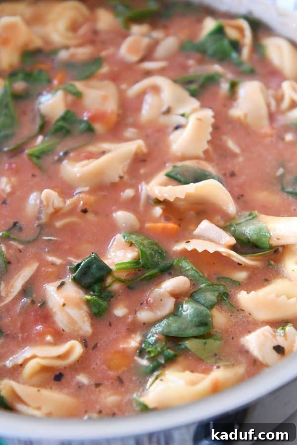 A large pot of creamy Tuscan tortellini soup simmering gently on a stovetop, ready to be served.