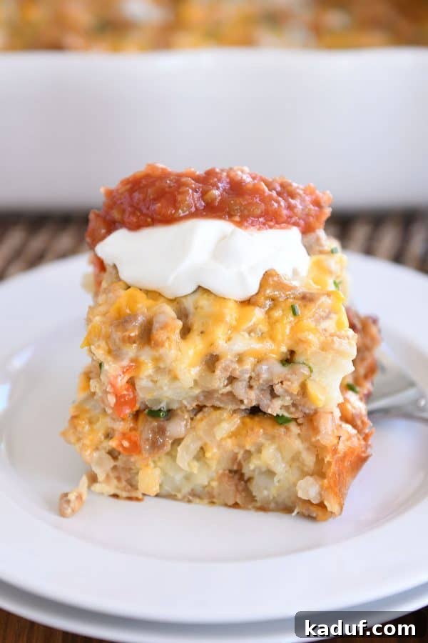 Dreamy Overnight Tater Tot Breakfast 4 Two squares of tater tot breakfast casserole stacked on each other on white plate with sour cream and salsa.
