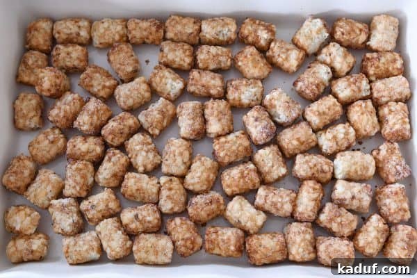 Dreamy Overnight Tater Tot Breakfast 5 Tater tots scattered in bottom of 9X13-inch baking pan.