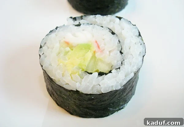 Homemade California Rolls Made Easy 4 A top-down view of a single California sushi roll, sliced into bite-sized pieces and arranged neatly on a white plate, highlighting the even cuts and fresh ingredients.