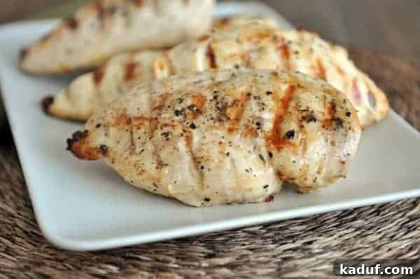 Caribbean Charred Chicken 2 Perfectly grilled chicken breasts, golden brown and juicy, served on a pristine white plate, adorned with fresh herbs, ready to be enjoyed.