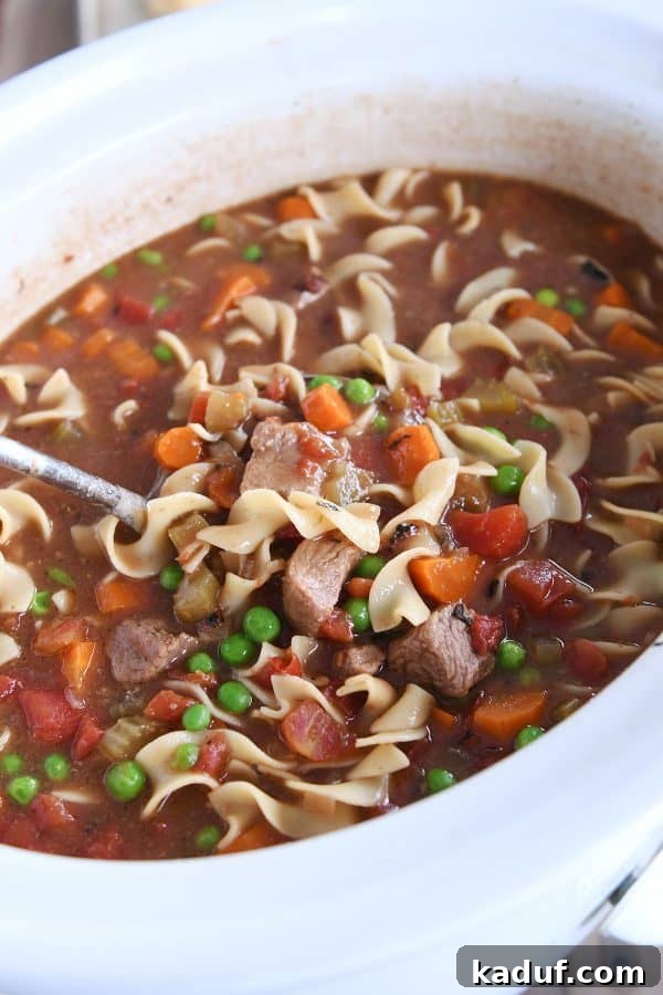 Hearty Slow Cooker Beef and Veggie Noodle Soup 3 White slow cooker filled with hearty beef vegetable noodle soup.