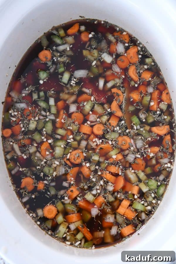 Hearty Slow Cooker Beef and Veggie Noodle Soup 6 Top down view of beef broth covering the meat and vegetables in the slow cooker, ready for cooking.