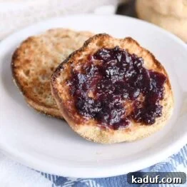 split open easy homemade english muffin with butter and jam on white plate